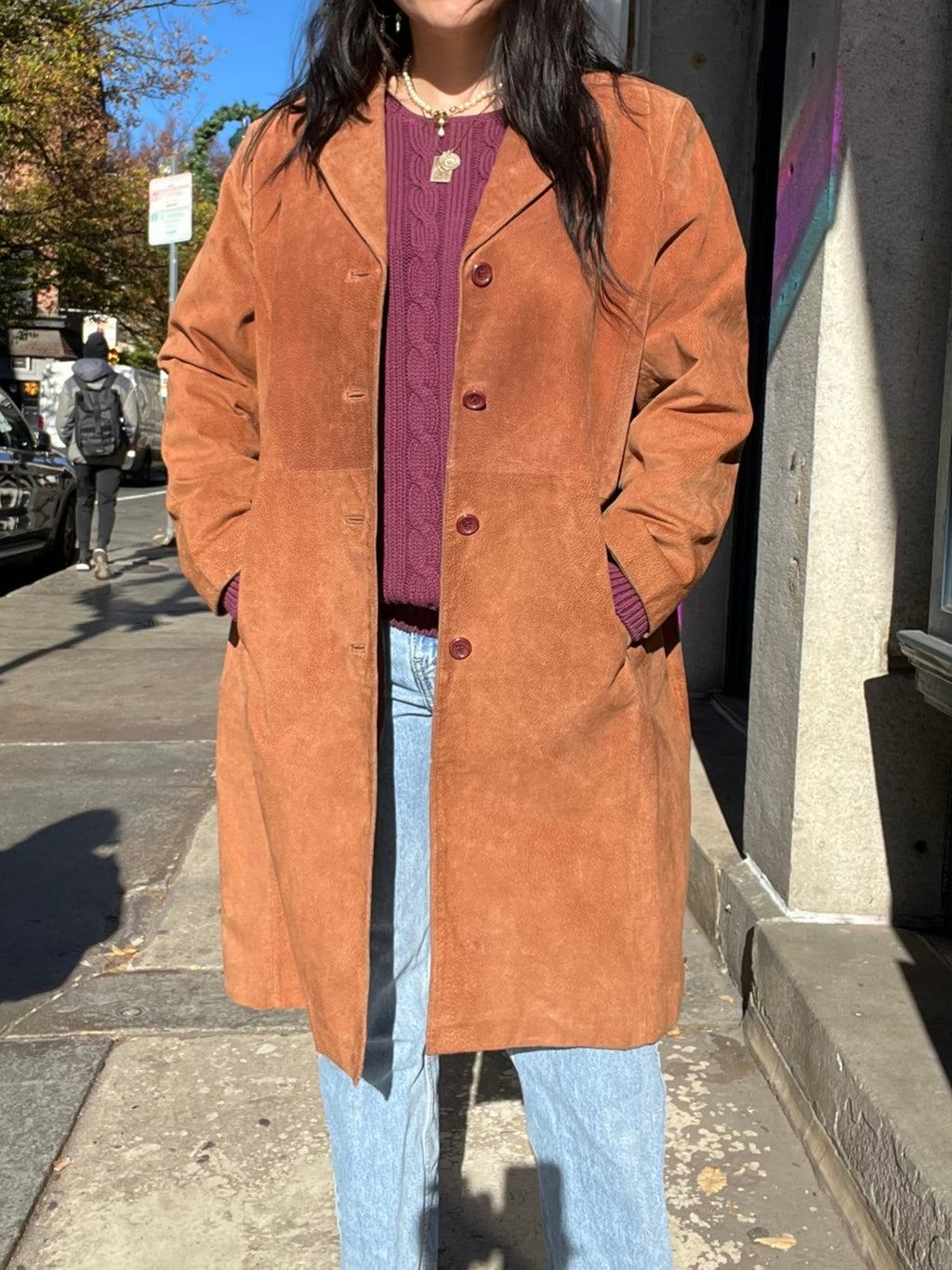 Elektra Vintage suede coat hanging on a wooden hanger, showcasing its classic vintage style and soft brown suede material.