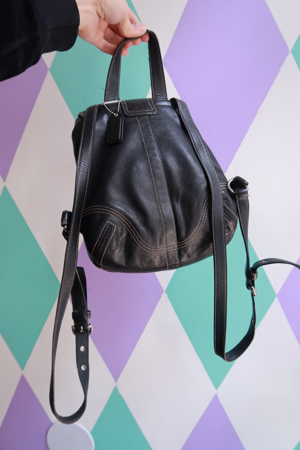 Vintage Coach Soho black leather backpack with drawstring closure and mini size, styled as a Y2K fashion accessory by Elektra Vintage.