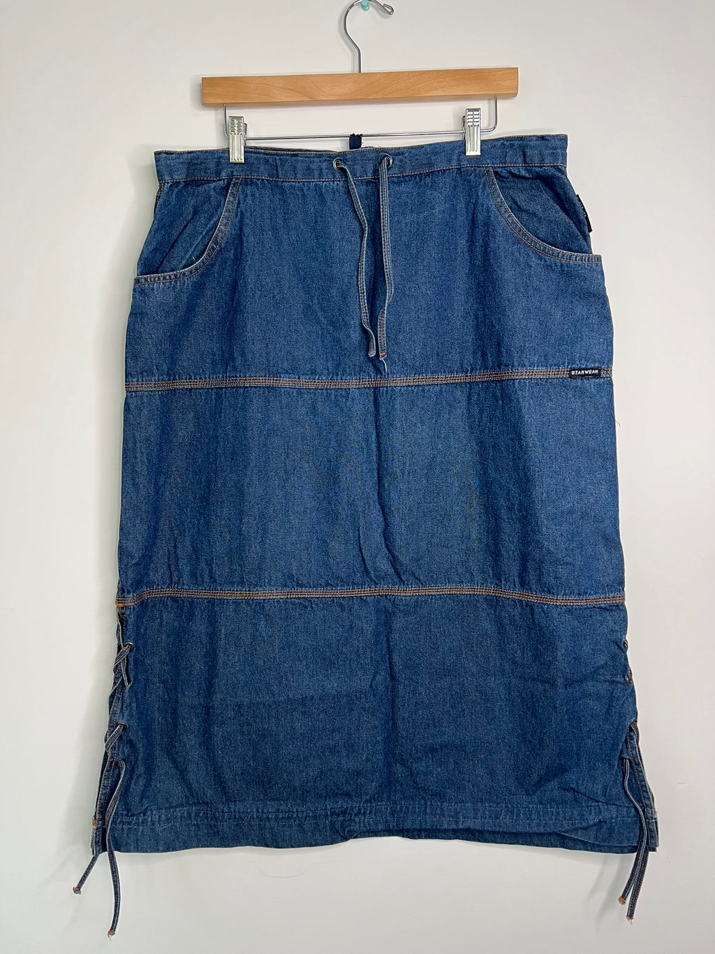 Vintage denim midi skirt by Elektra Vintage, featuring a classic blue wash and high waist, displayed on a hanger.