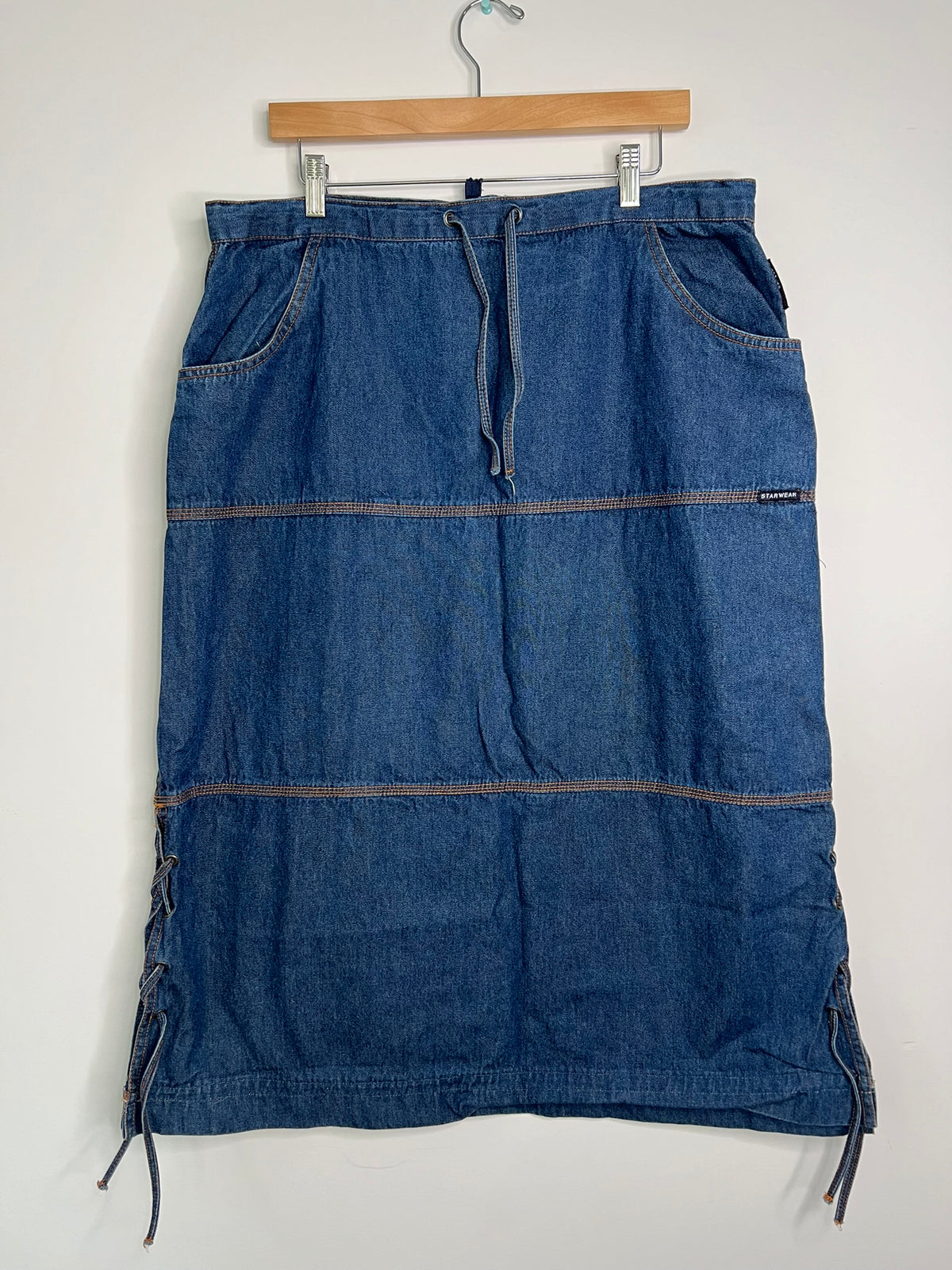 Vintage denim midi skirt by Elektra Vintage, featuring a classic blue wash and high waist, displayed on a hanger.