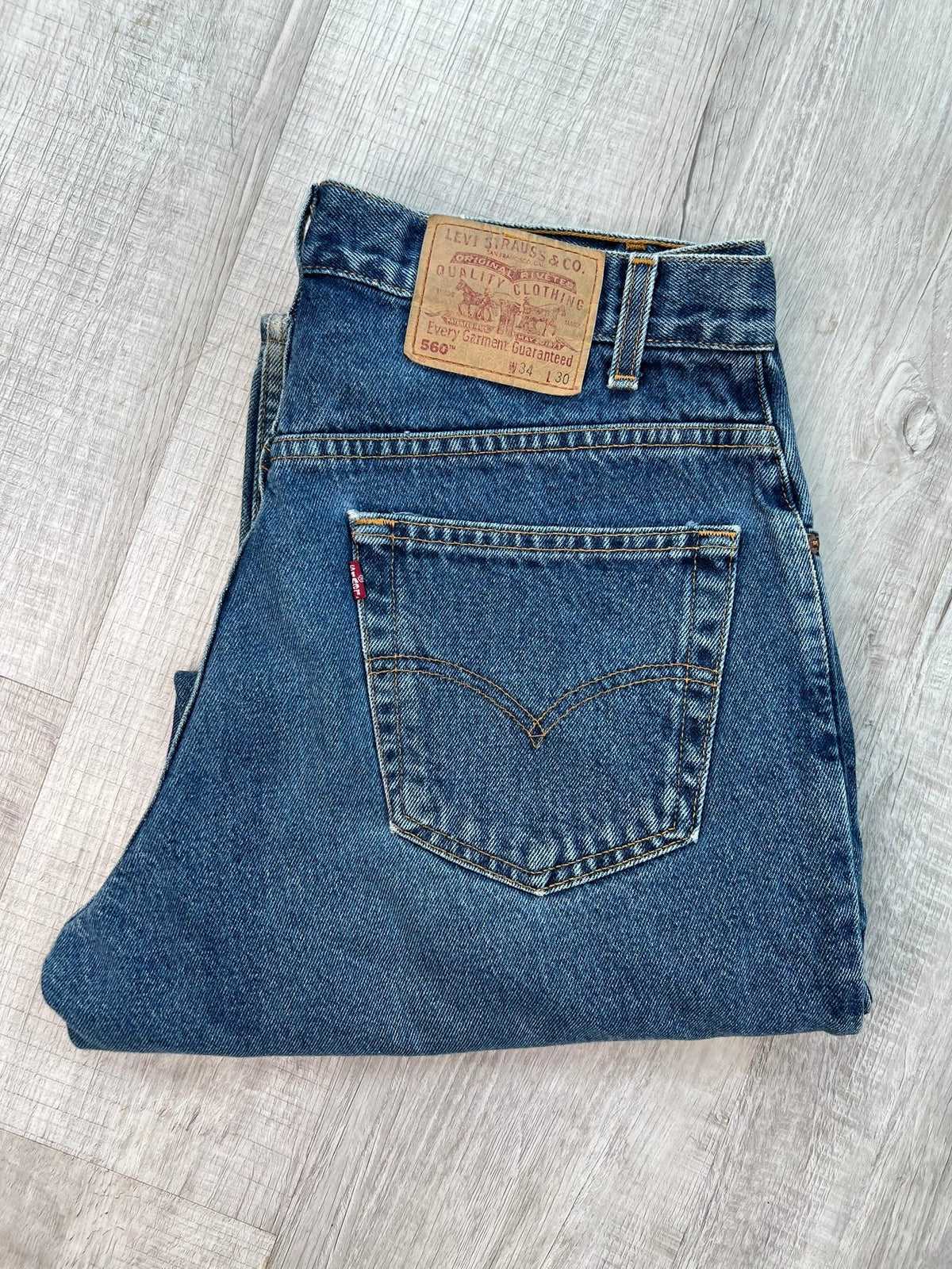 Elektra Vintage Levi's 560 loose fit tapered leg blue wash jeans displayed flat with front pockets and classic denim texture.