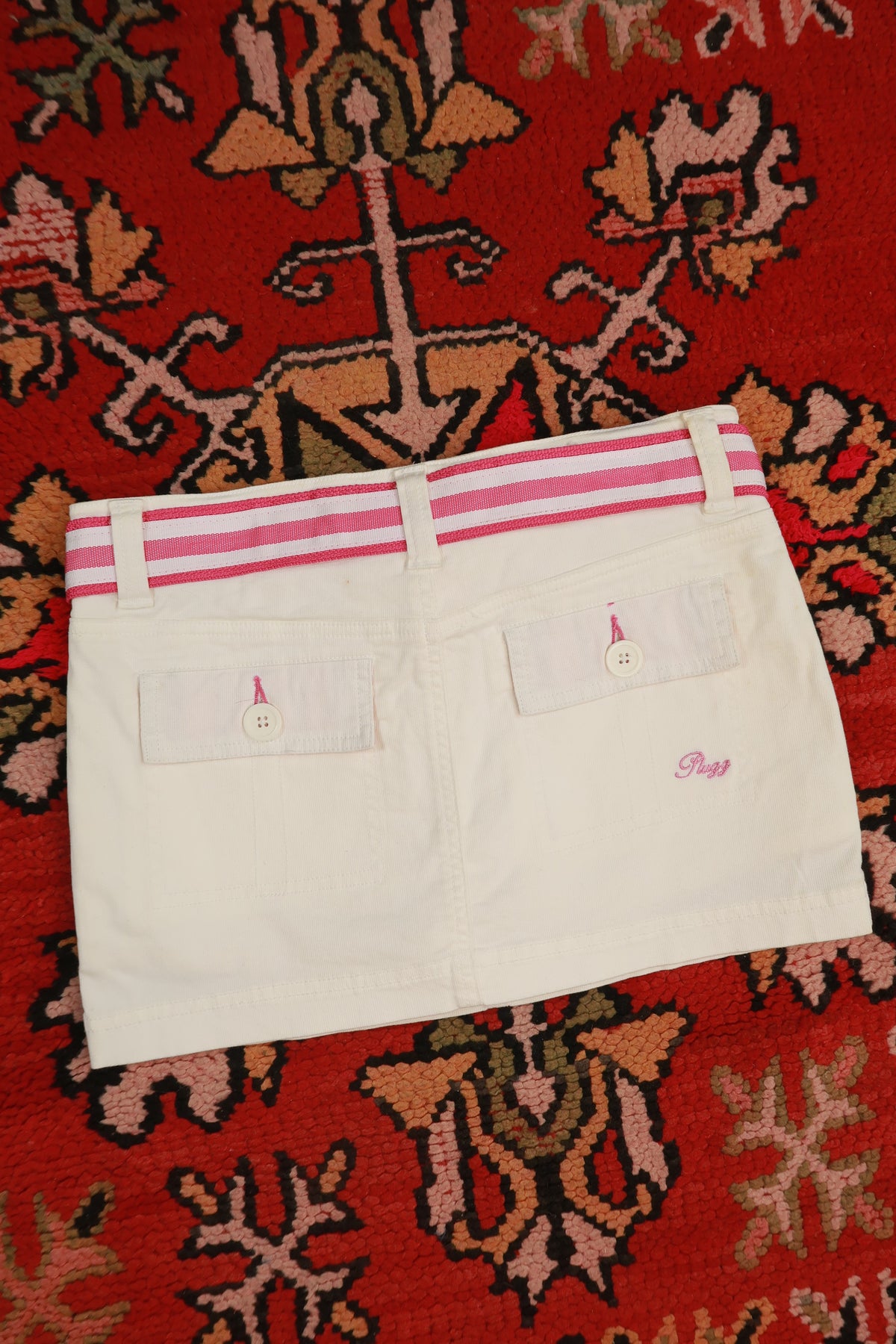 Vintage white denim mini skirt with pink stripe belt, by Elektra Vintage, featuring Y2K style and classic denim texture.