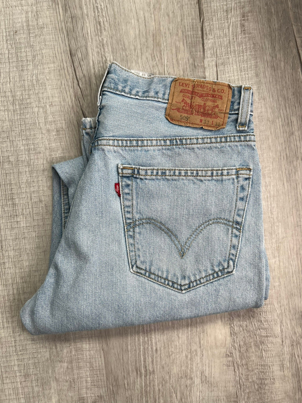 Light wash Levi's 505 regular fit jeans for men, displayed on a hanger, showcasing classic denim style and straight-leg cut.