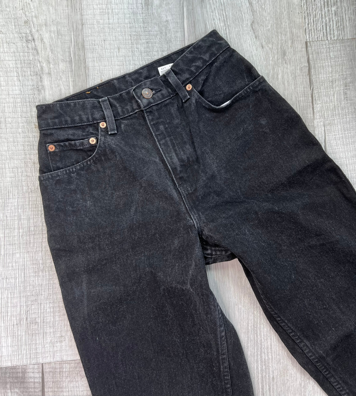 Vintage black Levi's 551 relaxed fit tapered leg jeans displayed on a wooden surface with a casual folded design.