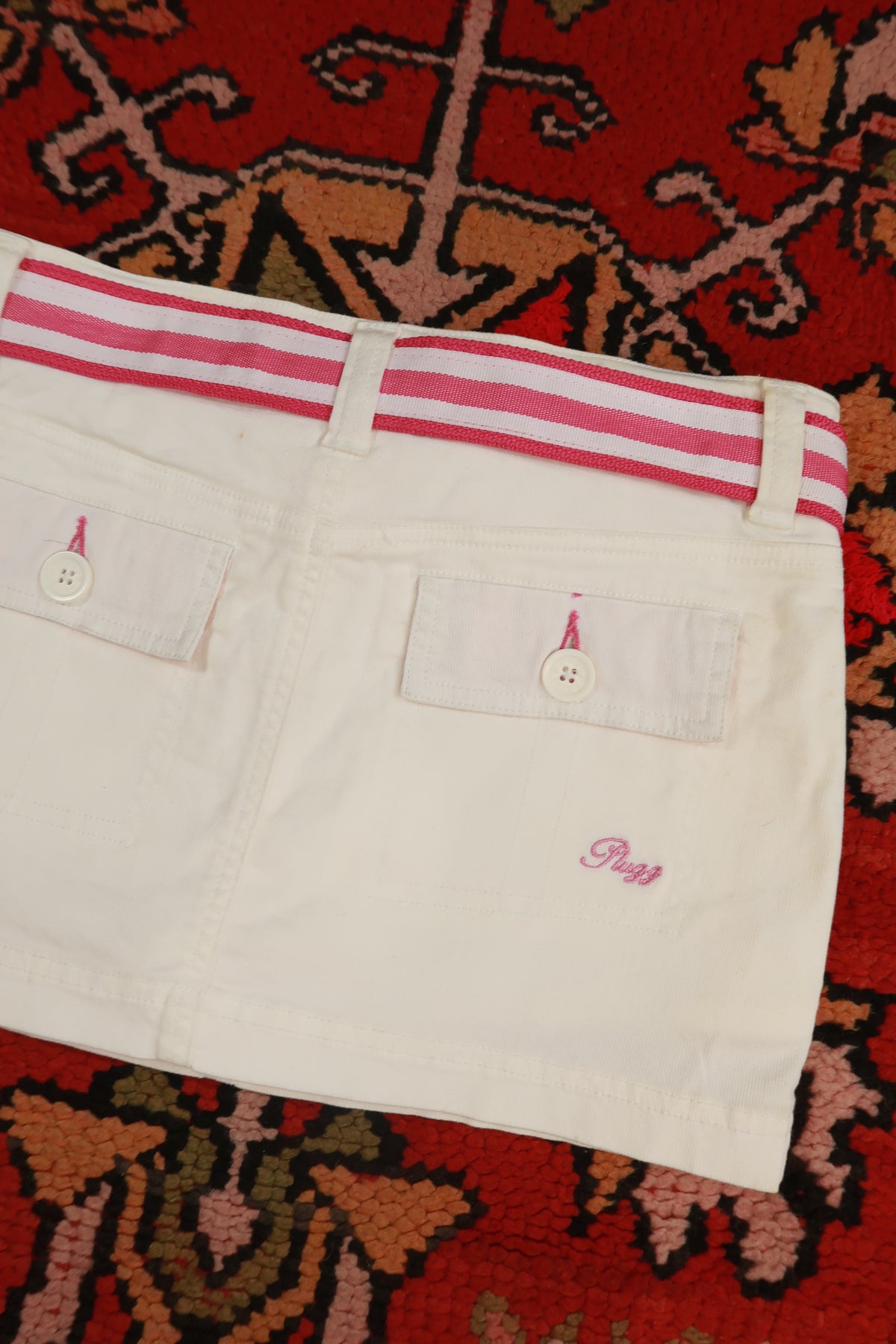 Vintage white denim mini skirt with pink stripe belt from Elektra Vintage, Y2K style, shown on a model.