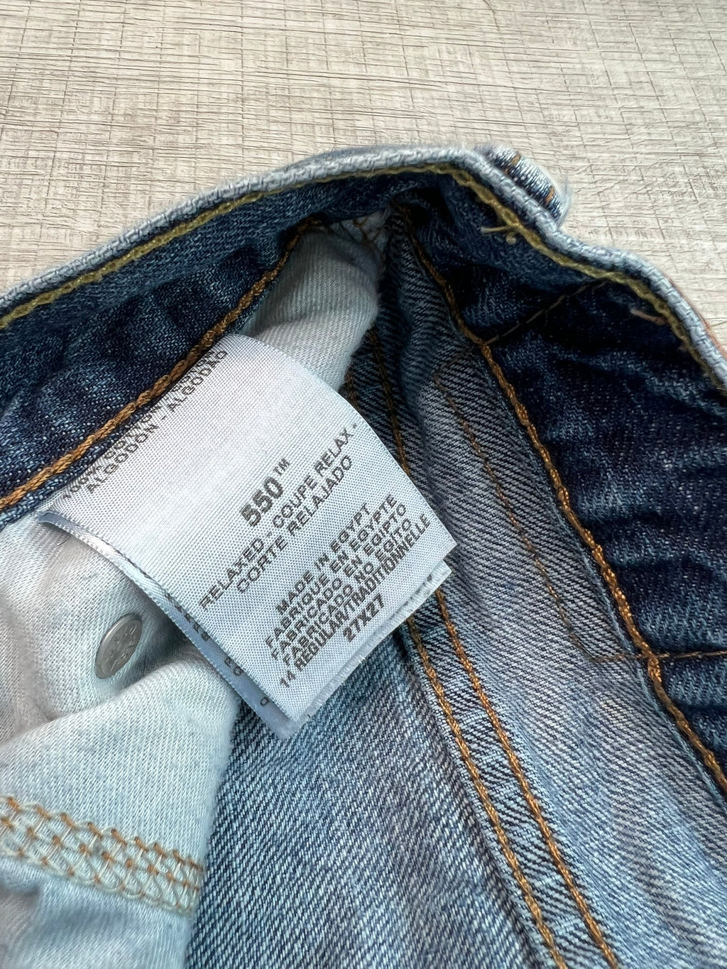 Women's Levi's 550 medium wash straight fit jeans with classic five-pocket design and belt loops, shown on a hanger.