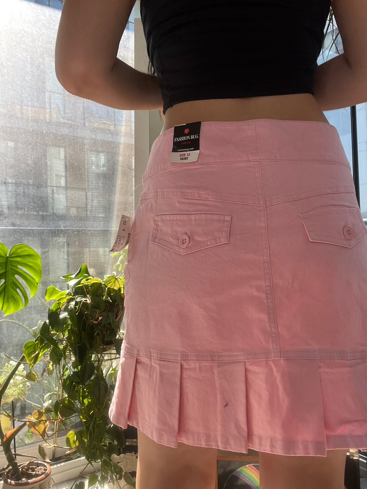 Vintage pink pleated skirt by Elektra Vintage, 2000s style with high waist and flowing fabric, displayed on a hanger.