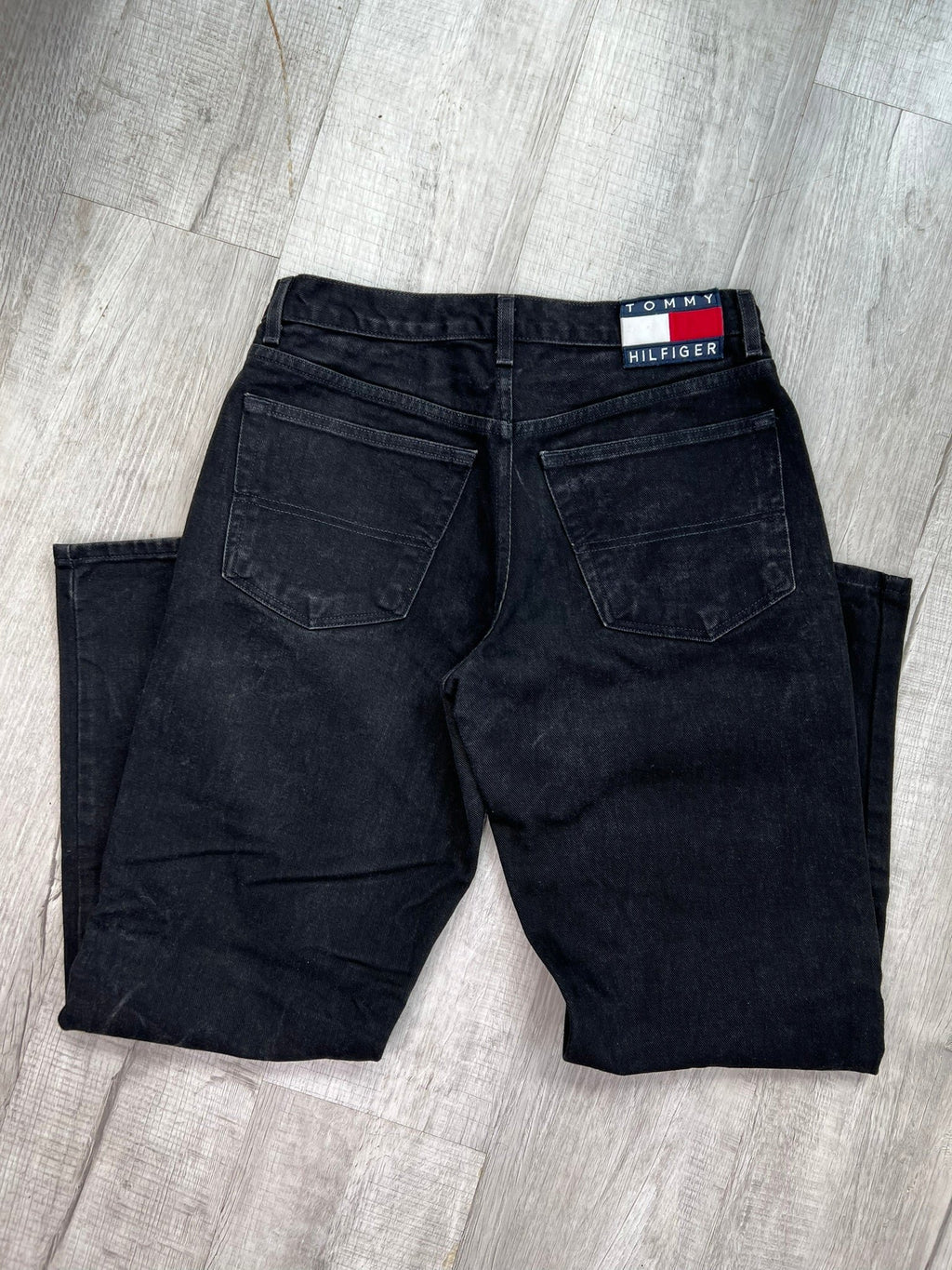 Relaxed fit black wash Tommy Hilfiger jeans for men, showing the denim fabric and classic five-pocket design.
