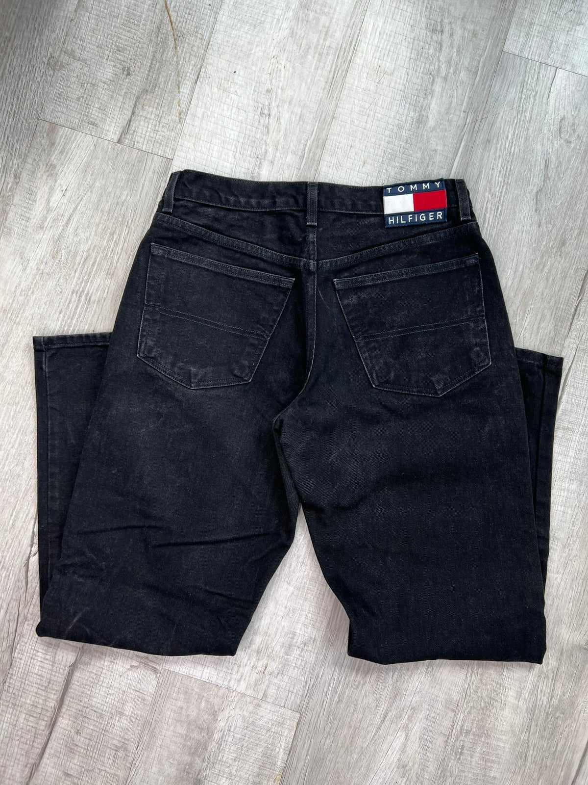 Relaxed fit black wash Tommy Hilfiger jeans for men, showing the denim fabric and classic five-pocket design.