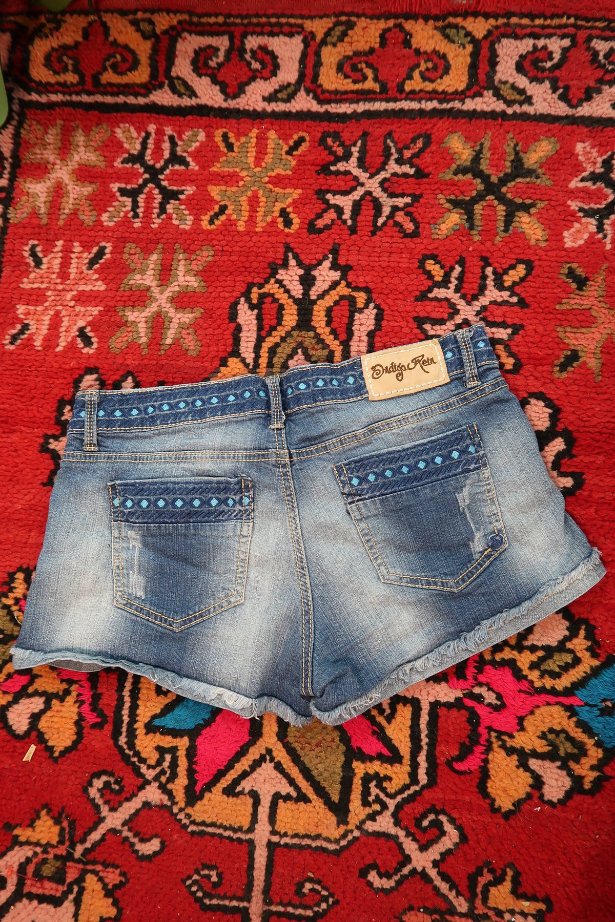 Women's distressed denim shorts with embroidered waistband by Elektra Vintage, showing frayed edges and stylish detailing.
