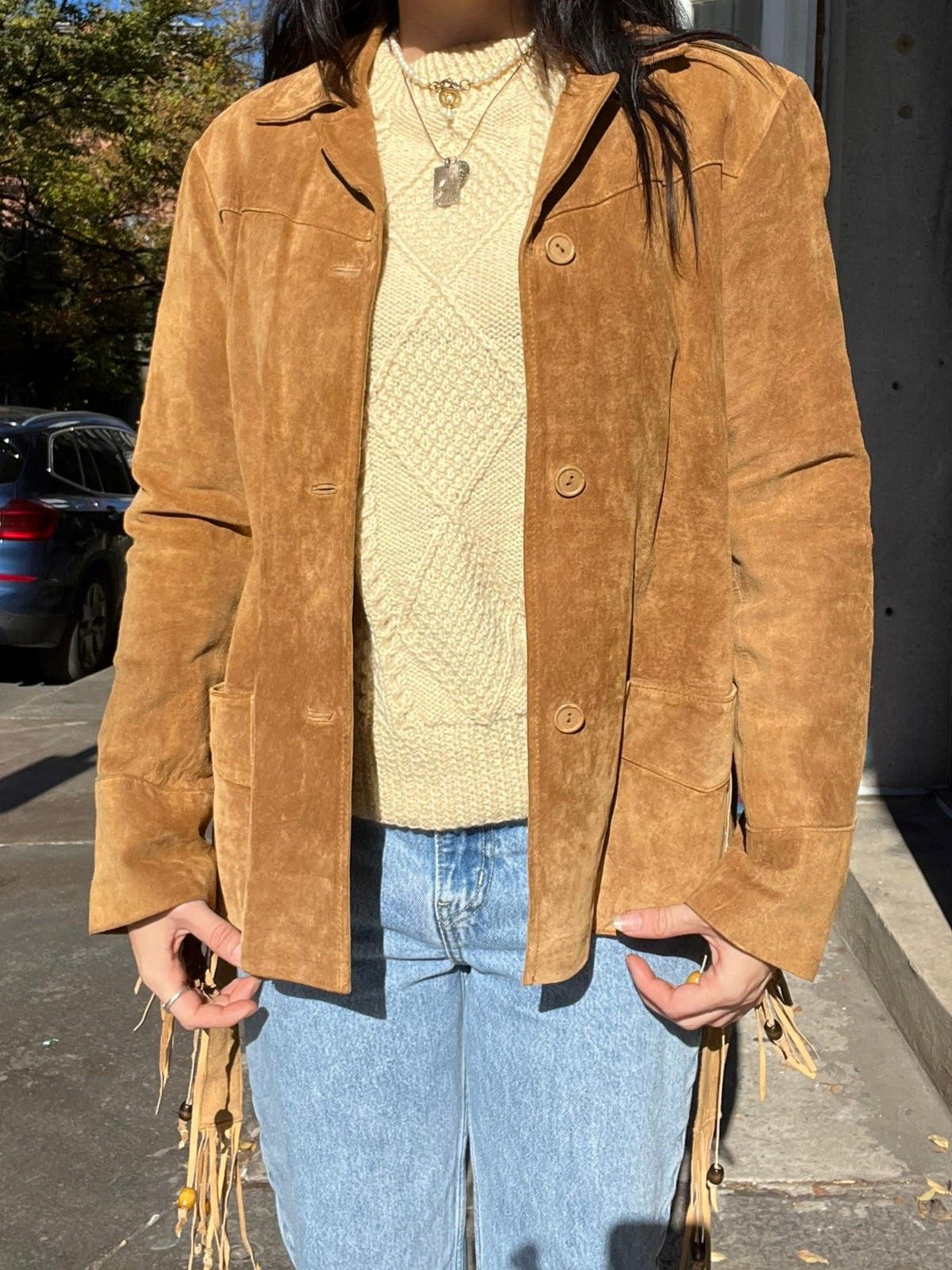 Elektra Vintage vintage suede fringe tassel coat hanging on a wooden hanger, showcasing its bohemian style and detailed fringe design.