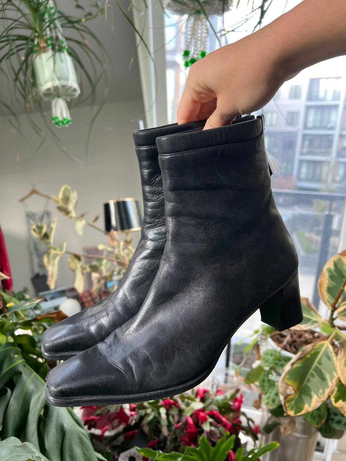 Vintage Stuart Weitzman square toe boots in black leather, displayed on a wooden surface.