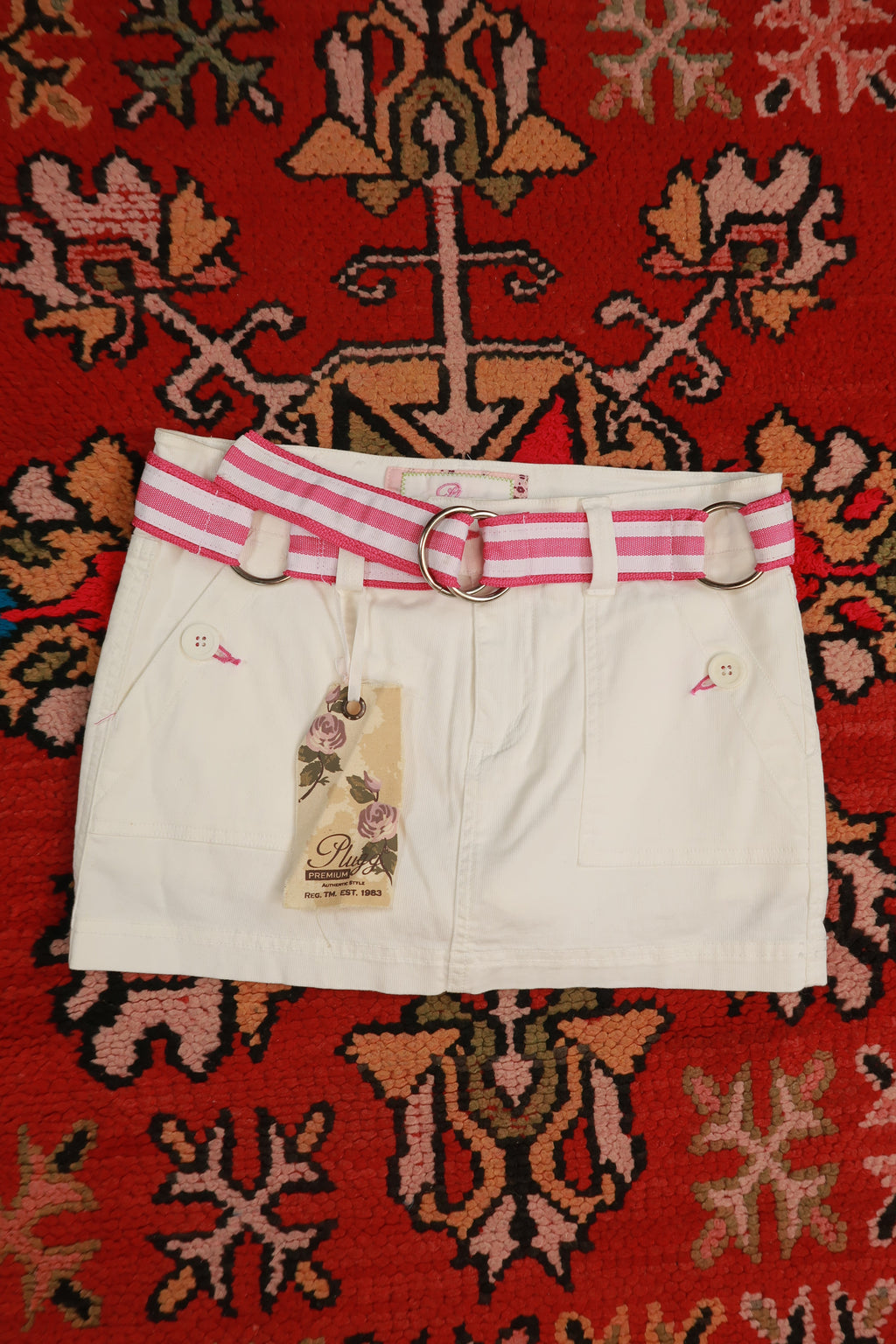 Vintage white denim mini skirt by Elektra Vintage with pink stripe belt, Y2K style, casual and trendy fashion piece.