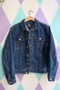 Vintage Tommy Hilfiger denim jacket, 2000s classic blue jean trucker style, with visible button closures and distressed details.