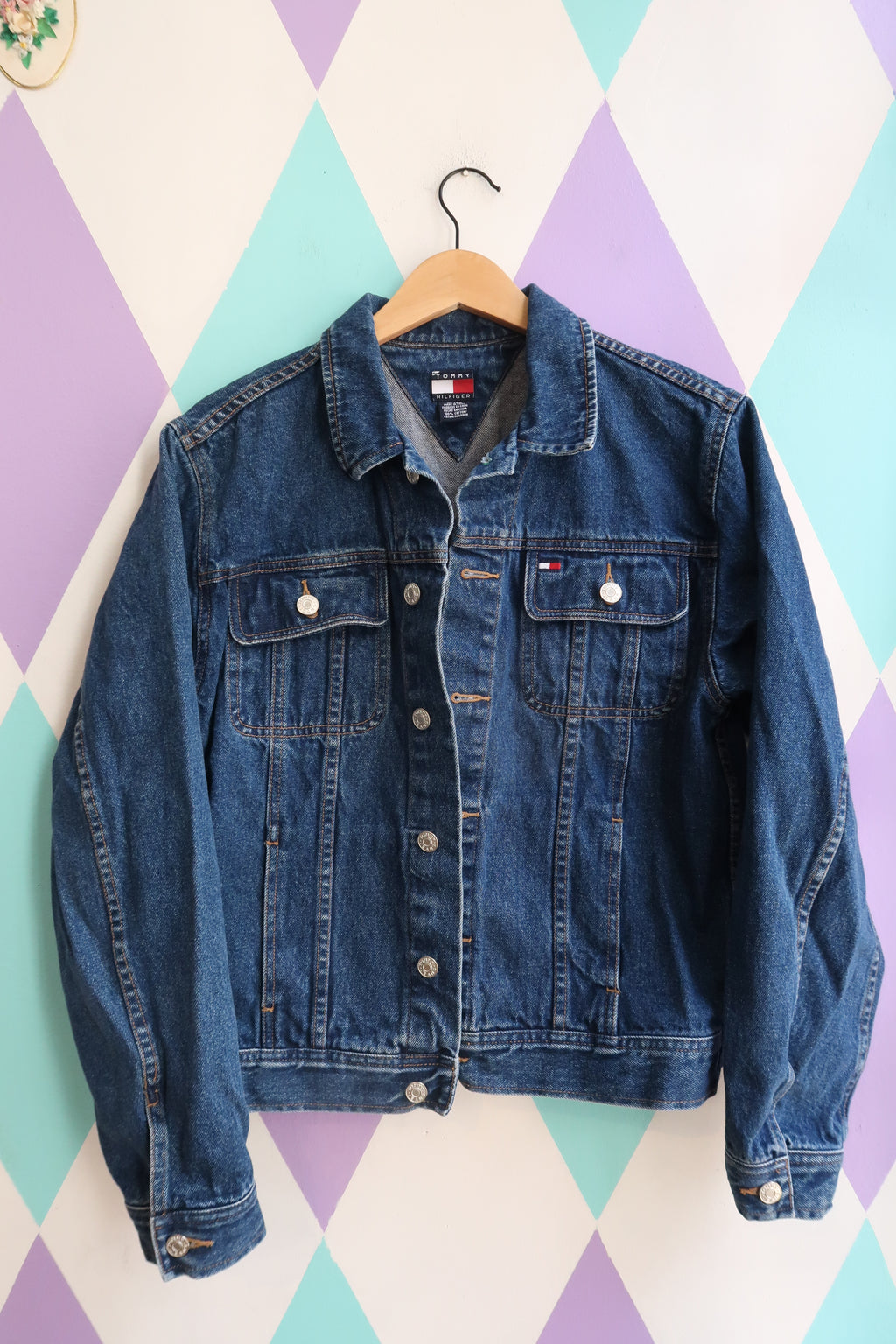 Vintage Tommy Hilfiger denim jacket from the 2000s, classic blue jean trucker style, featuring traditional stitching and button details.