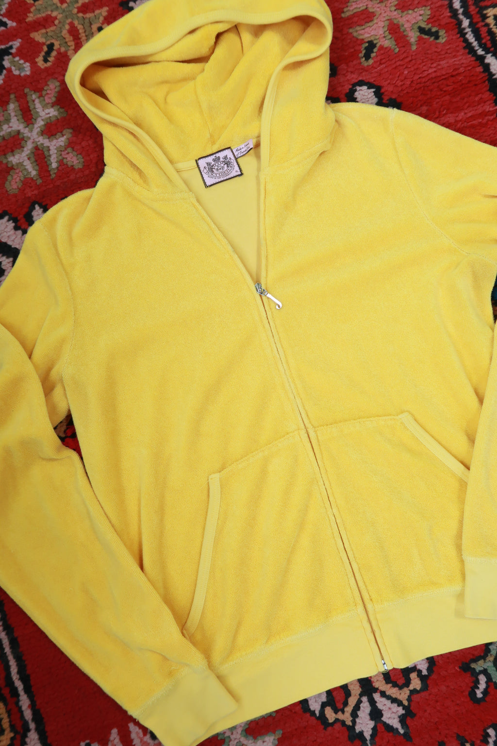 Vintage yellow Juicy Couture terry cloth zip-up hoodie by Elektra Vintage laid flat, showing front view with zipper and hood.