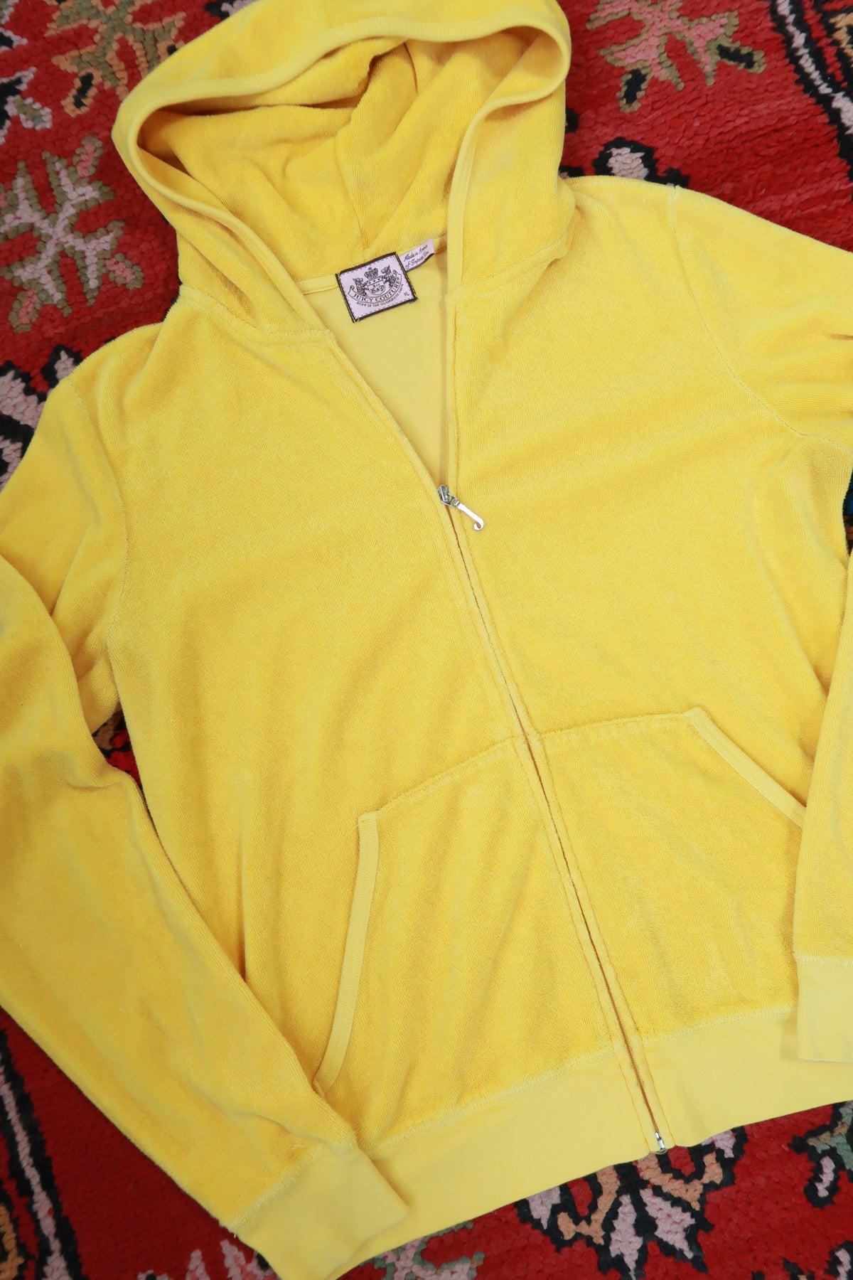 Vintage yellow Juicy Couture terry cloth zip-up hoodie by Elektra Vintage laid flat, showing front view with zipper and hood.