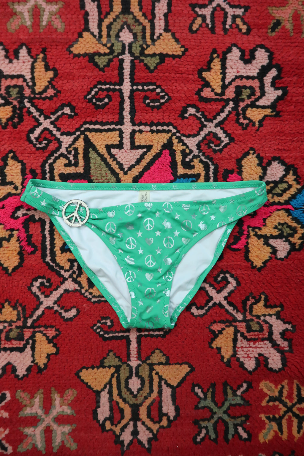 Vintage Victoria’s Secret green peace sign bikini bottoms by Elektra Vintage with Y2K silver foil detail, displayed on a white background.