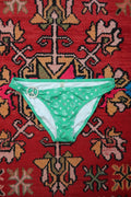 Vintage Victoria’s Secret green peace sign bikini bottoms by Elektra Vintage with Y2K silver foil detail, displayed on a white background.