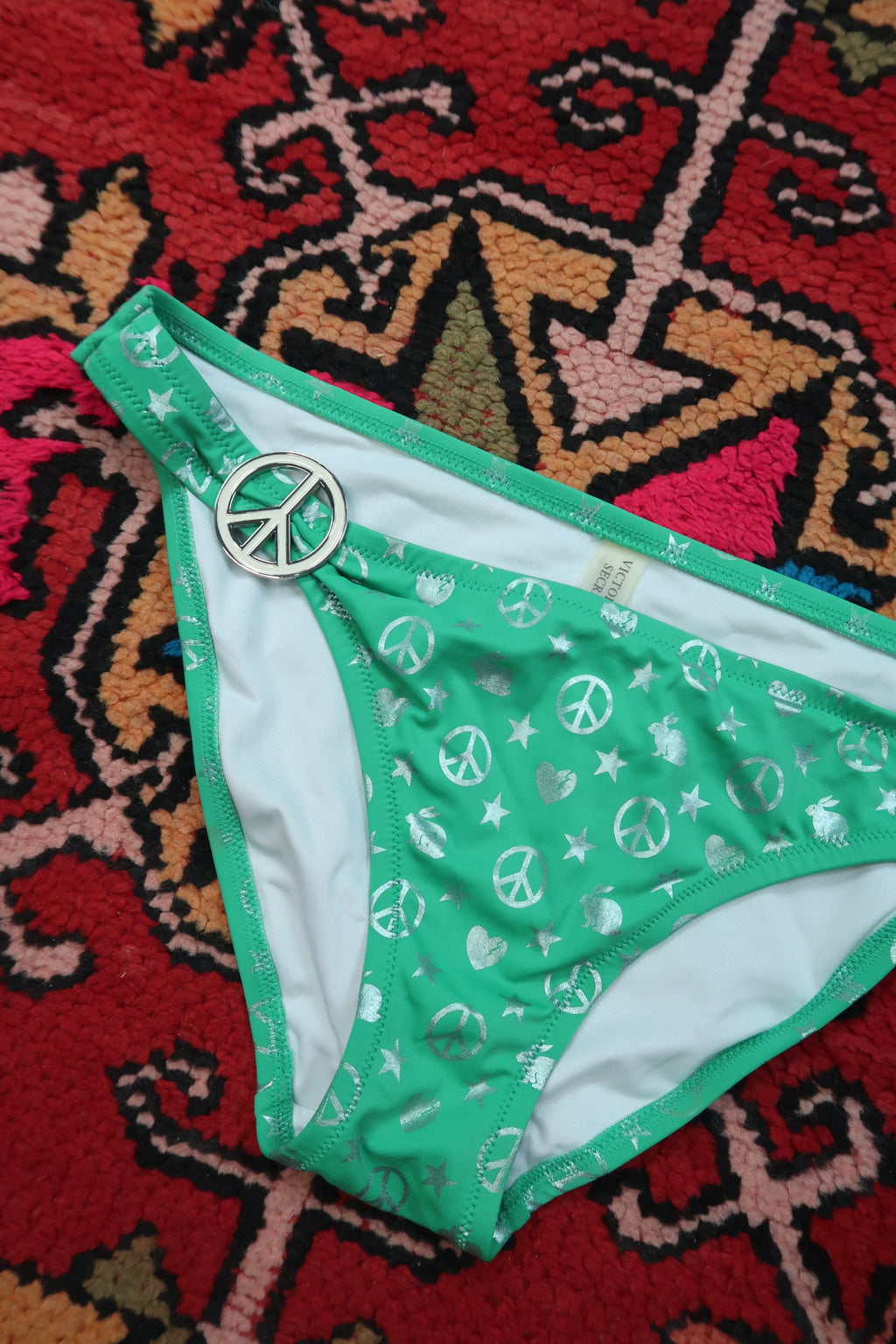 Vintage Victoria’s Secret green peace sign bikini bottoms by Elektra Vintage, featuring Y2K silver foil swimwear design.