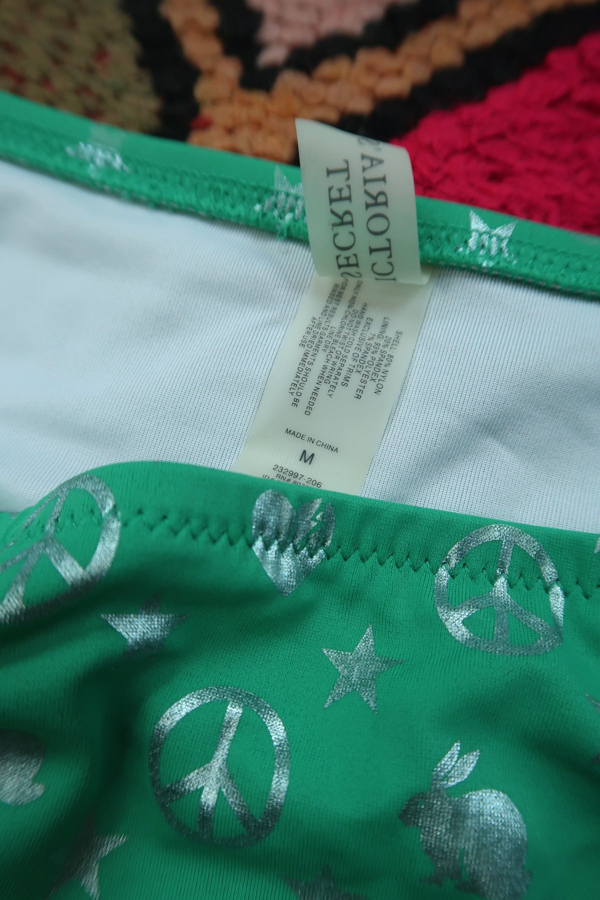 Vintage Victoria’s Secret green peace sign bikini bottoms with silver foil, Y2K style, by Elektra Vintage, shown on a model.
