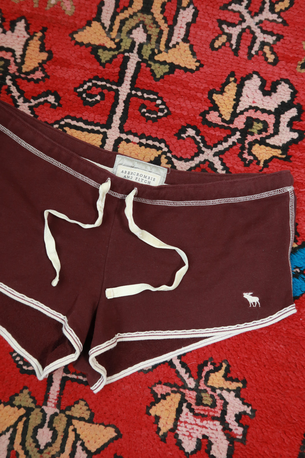 Women's vintage burgundy dolphin shorts by Abercrombie & Fitch, styled with Elektra Vintage branding on a casual outfit.