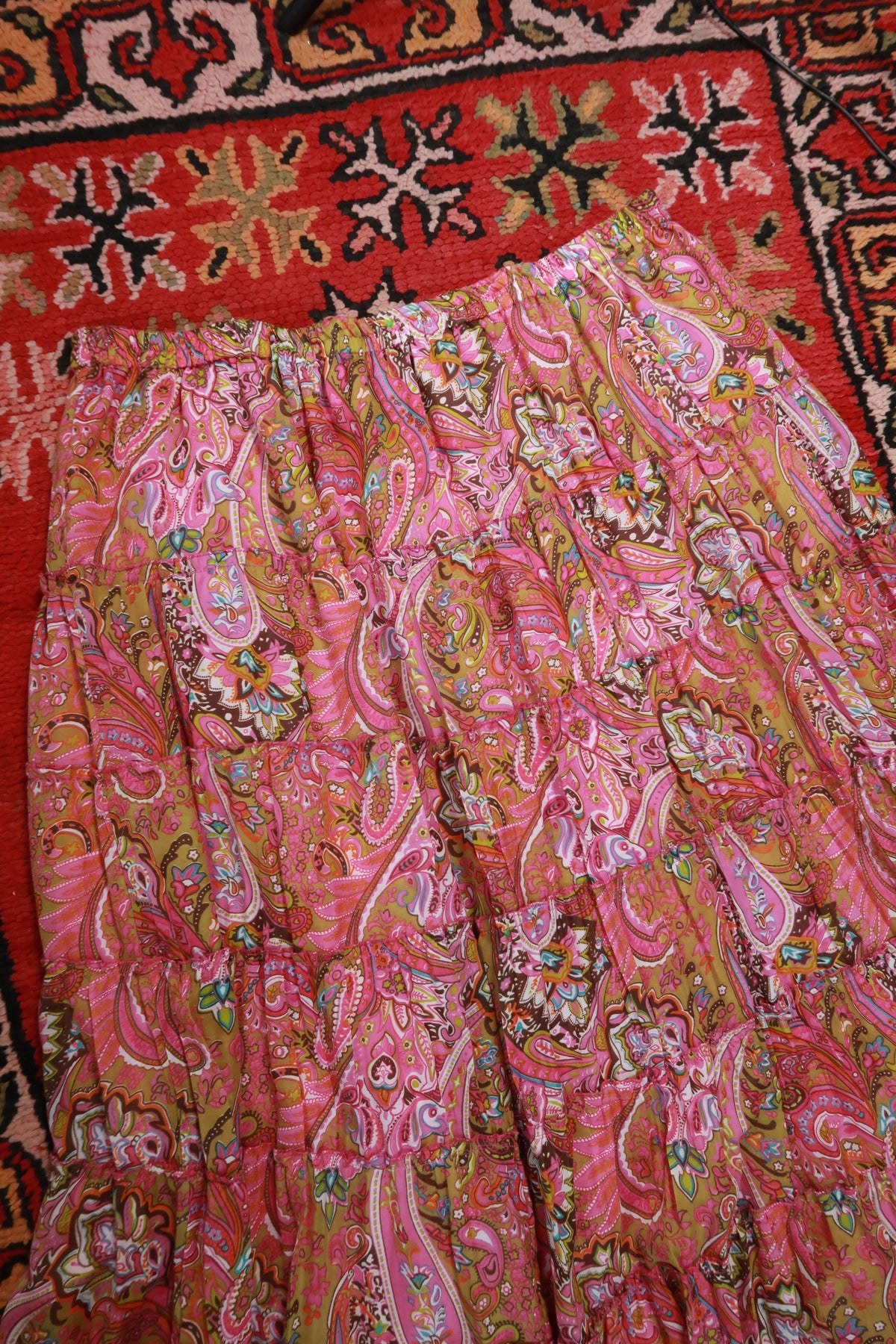 Vintage pink paisley boho midi skirt by Elektra Vintage featuring tiered design and flowing fabric.