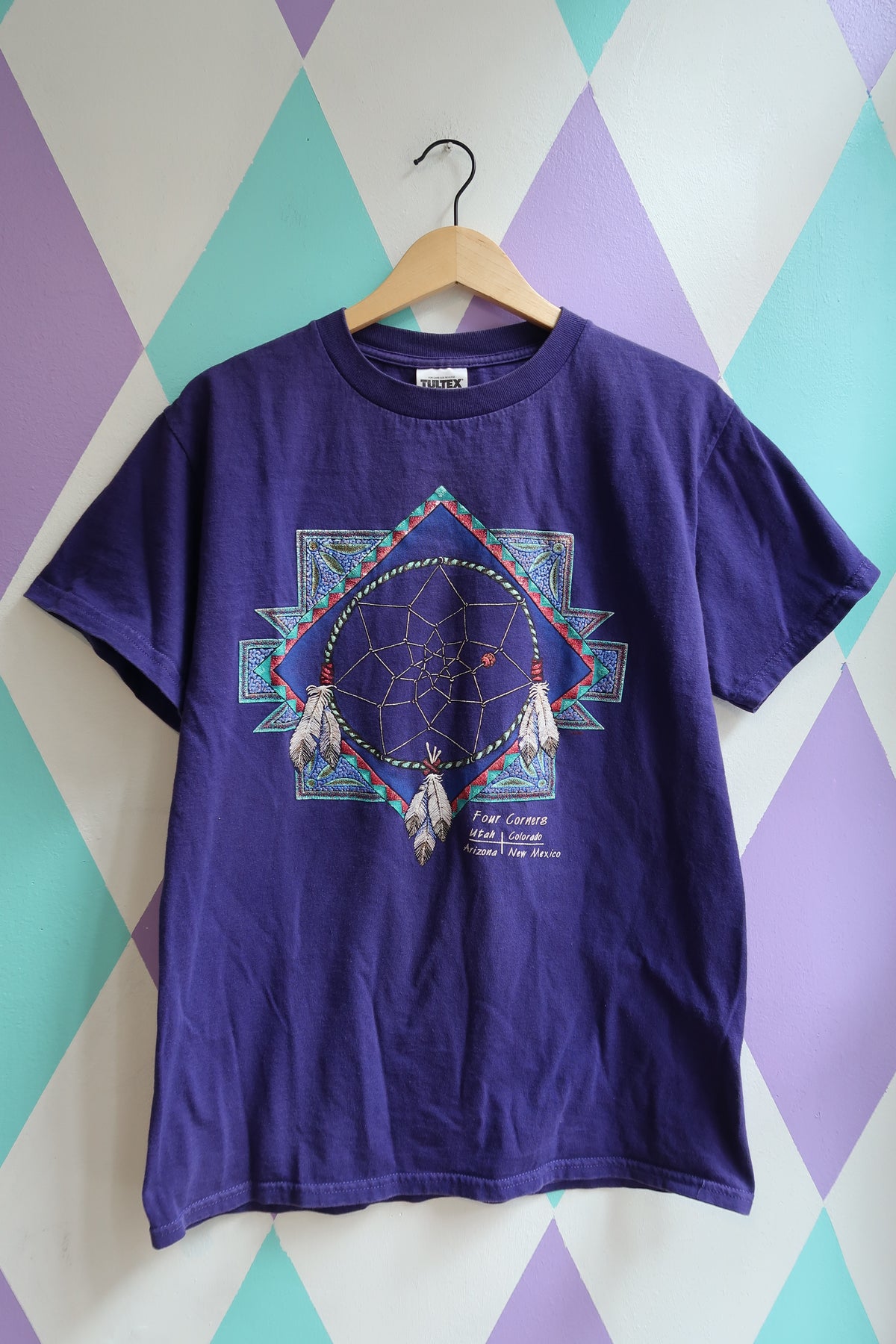 Purple t-shirt with a dreamcatcher design on a harlequin wall