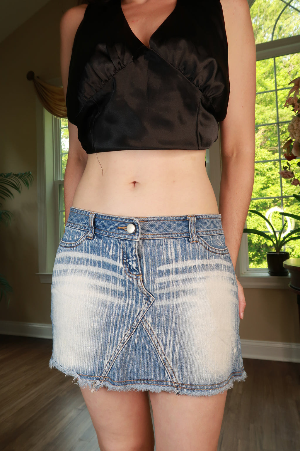 Vintage 2000s distressed denim mini skirt by Elektra Vintage, showing a worn, edgy style with frayed hem and classic denim texture.