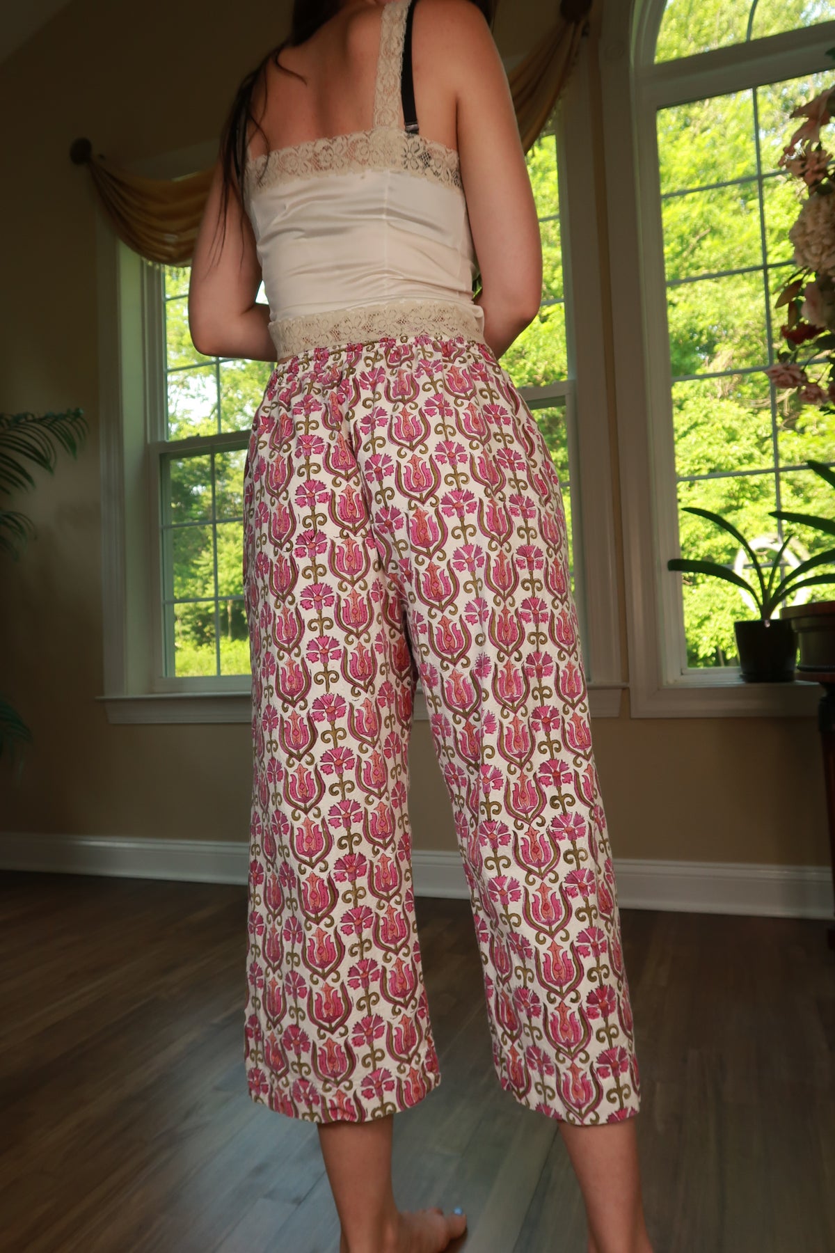 Vintage cotton pink floral print cropped wide-leg pants for women by Elektra Vintage, displayed on a hanger.