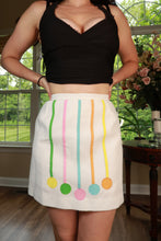Load image into Gallery viewer, Vintage white mod A-line mini skirt by Elektra Vintage with pastel ribbon appliqué, showcasing a retro-inspired skirt design.
