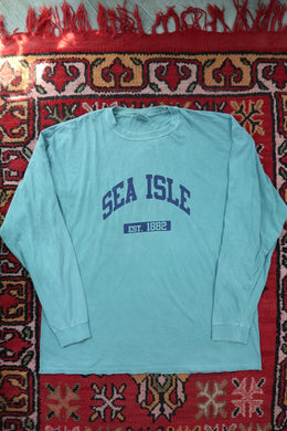 Light blue long sleeve tshirt with text on a red patterned rug