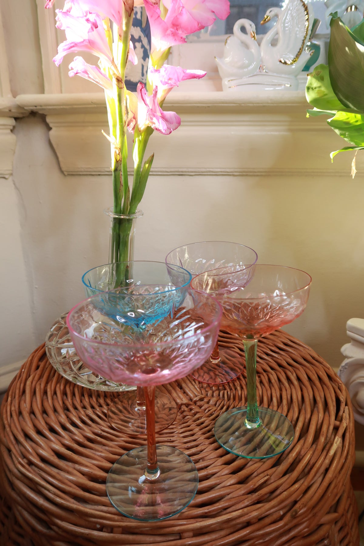 Set of four vintage pastel-colored coupe champagne glasses by Elektra Vintage, depression-style cocktail glasses on a reflective surface.