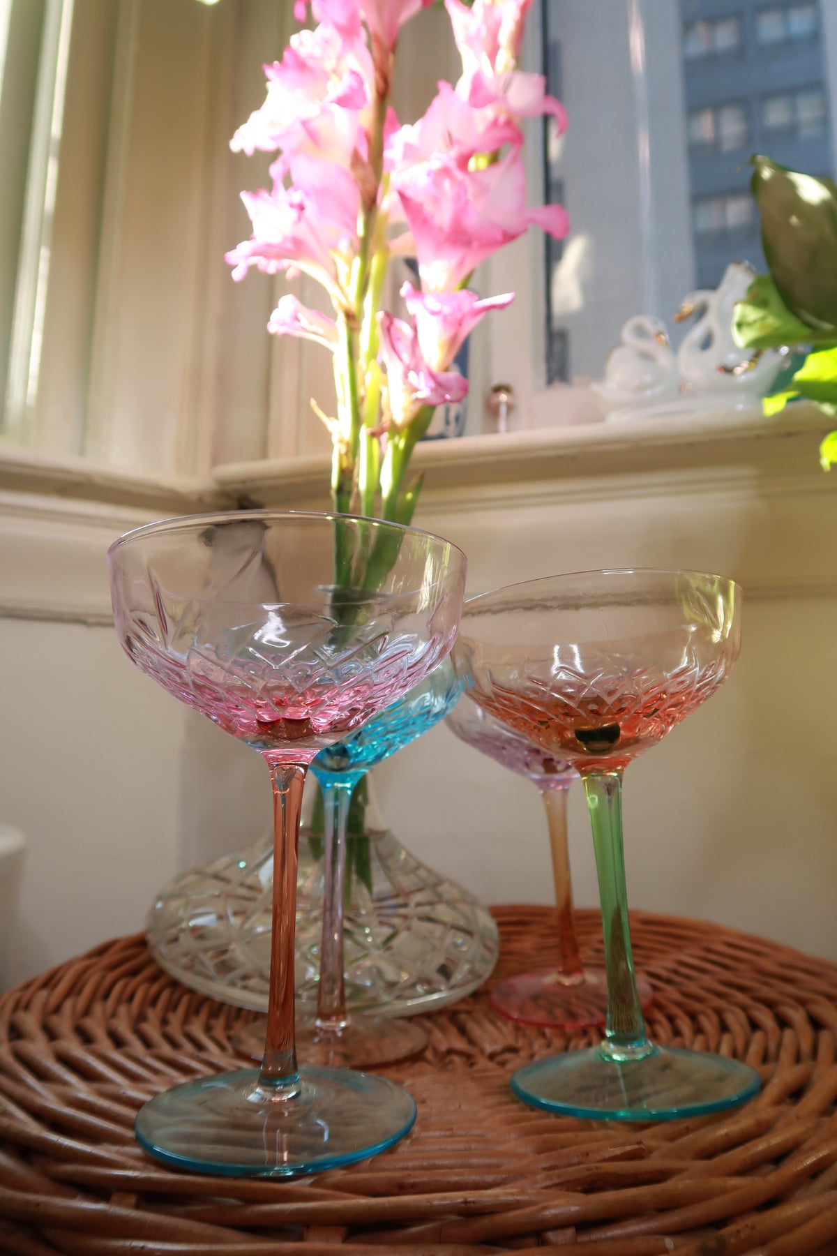 Set of four vintage pastel-colored coupe champagne glasses by Elektra Vintage, depression style cocktail glasses on a white background.