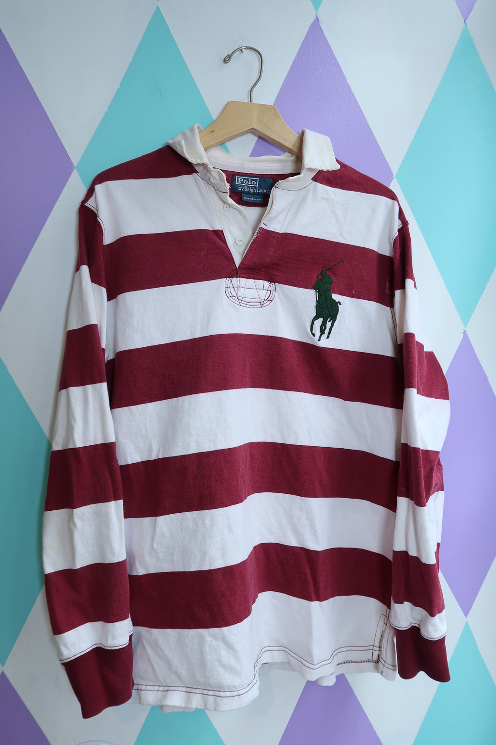 Maroon and white striped polo shirt on a colorful geometric patterned surface