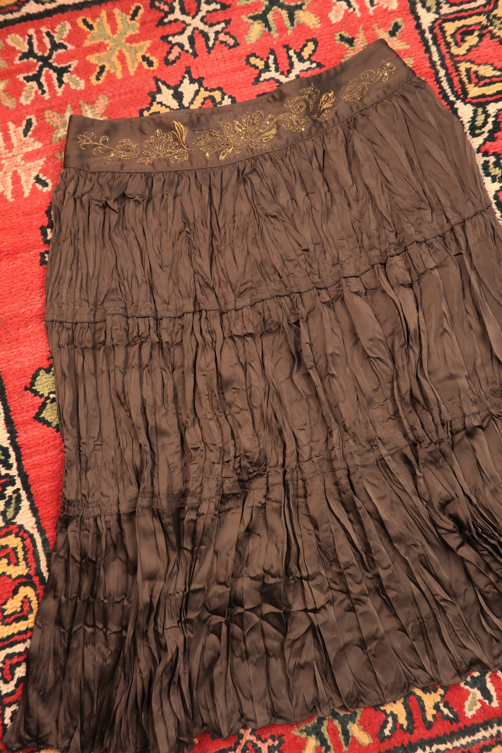 Vintage brown satin crepe midi skirt with gold embroidered waistband by Elektra Vintage displayed on a hanger.