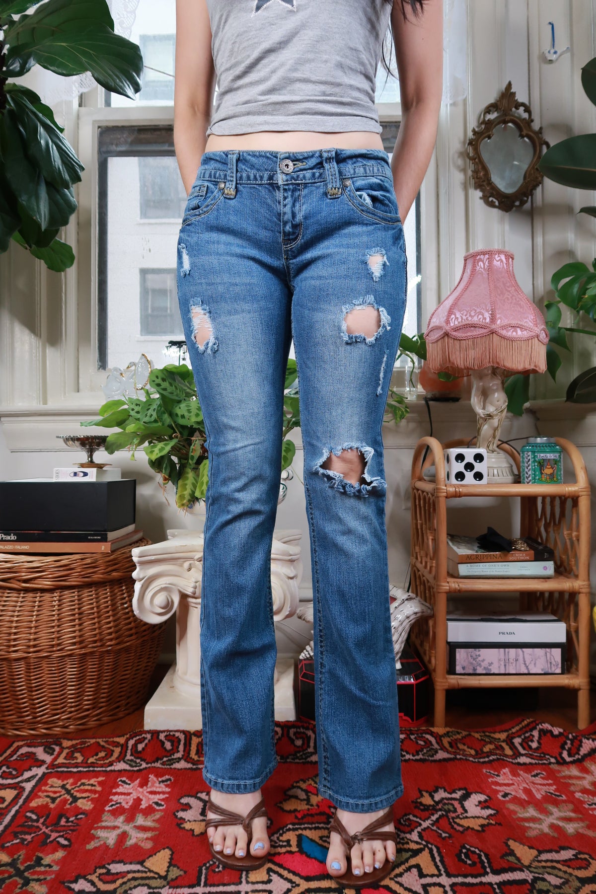 Women's vintage Y2K distressed low rise straight leg jeans by Elektra Vintage, showing faded denim and raw hem details.