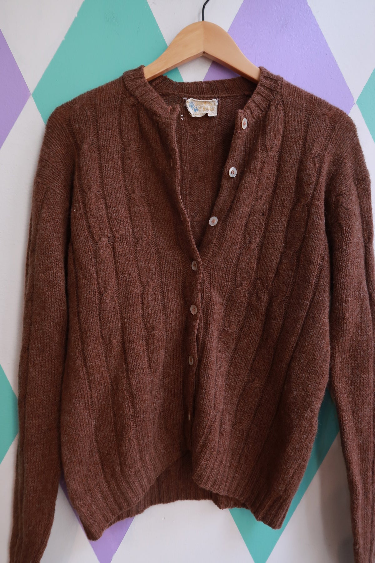 Vintage 1960s John Meyer brown wool button-up cardigan on a hanger, showcasing classic retro style and textured knit fabric.