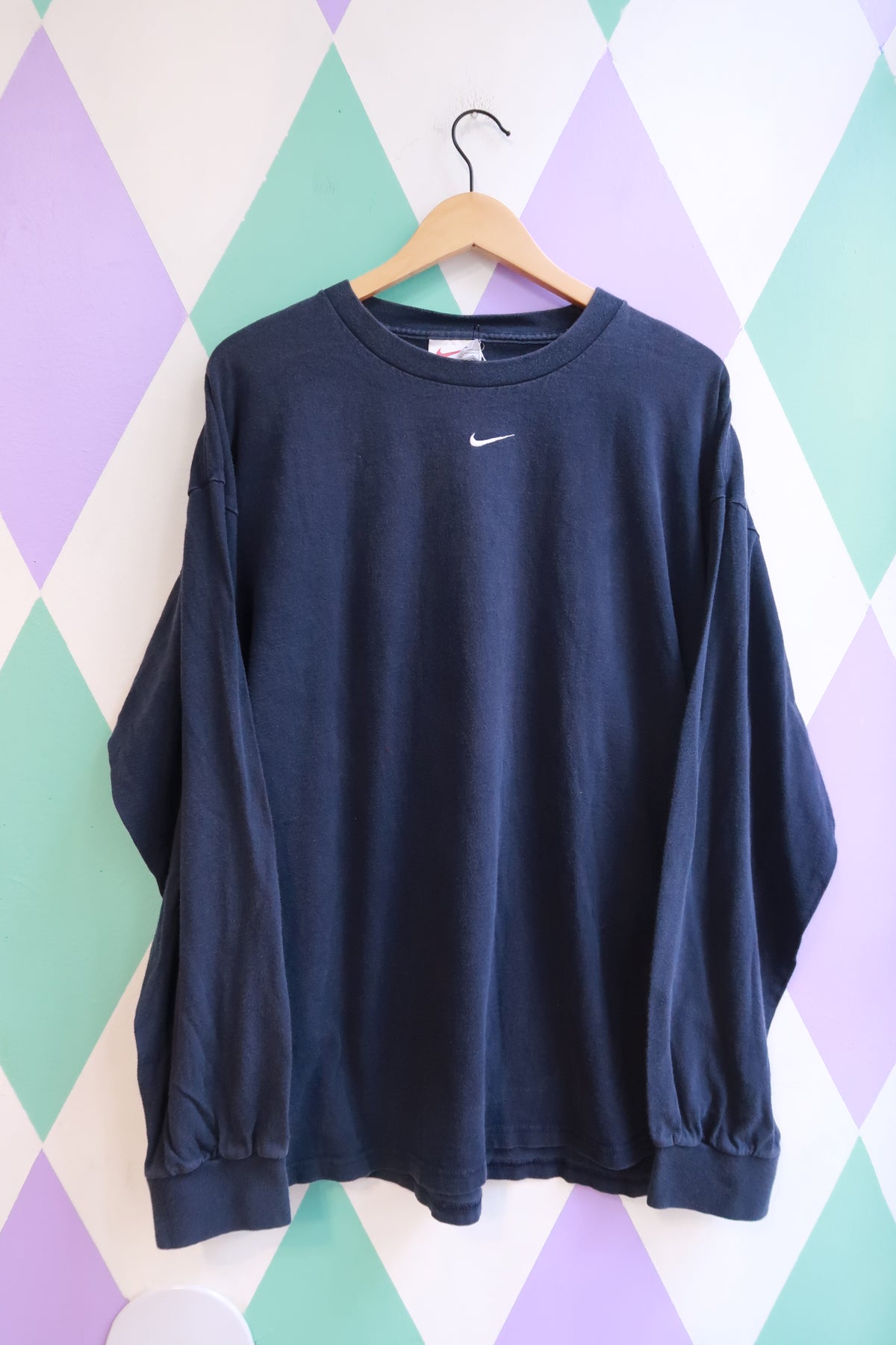 Vintage 2000s Nike navy long sleeve shirt with embroidered swoosh logo, styled casually on a hanger.