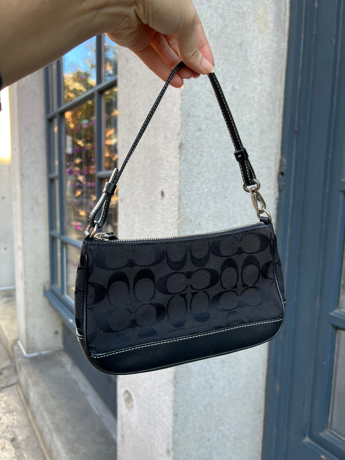 Vintage black Coach Signature C demi shoulder bag with leather trim, featuring the iconic logo pattern and a sleek, compact design.