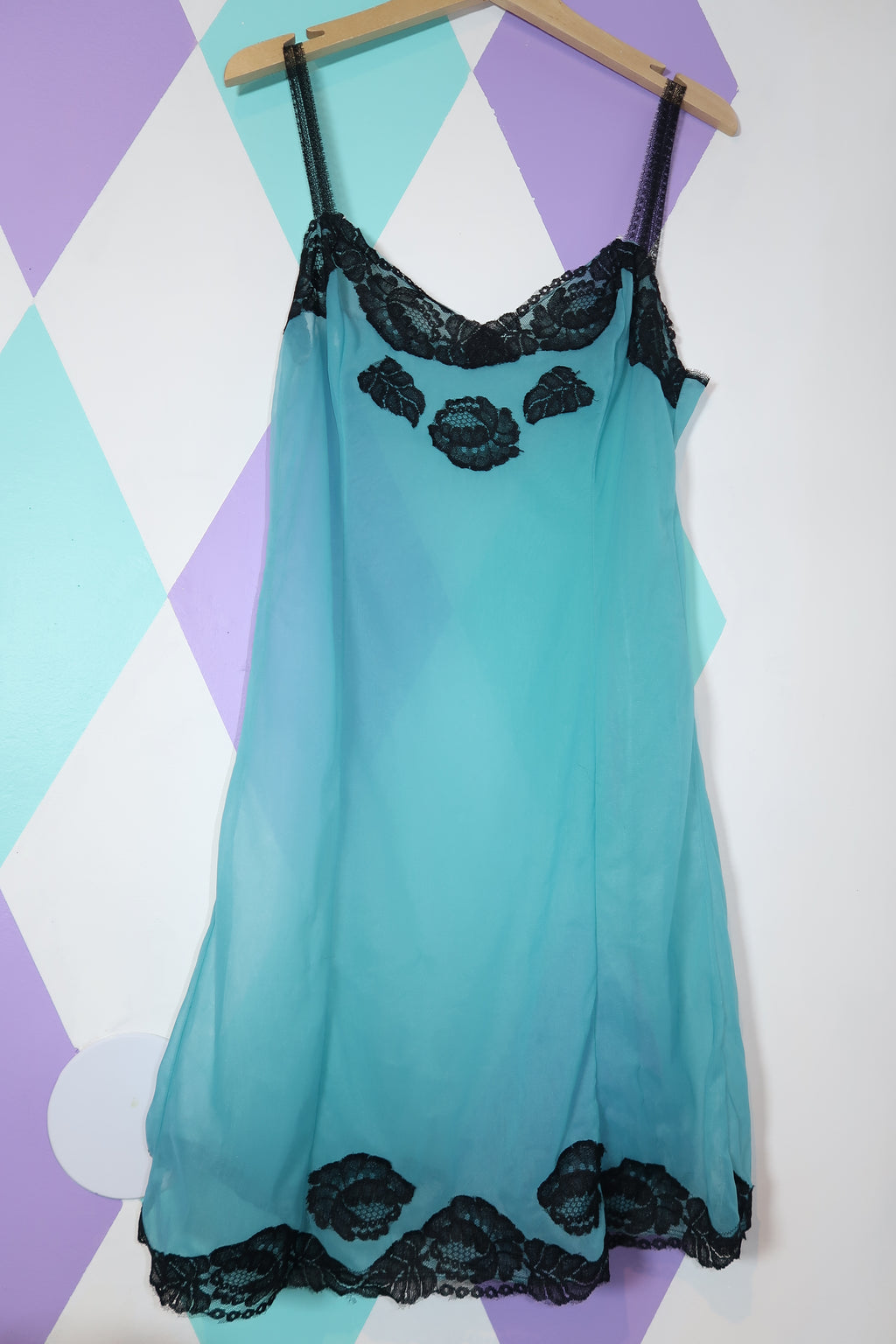 Elegant vintage sheer blue slip dress with black lace trim from Elektra Vintage, shown on a hanger.
