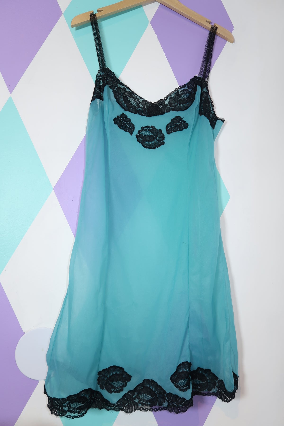 Elegant vintage sheer blue slip dress with black lace trim from Elektra Vintage, shown on a hanger.