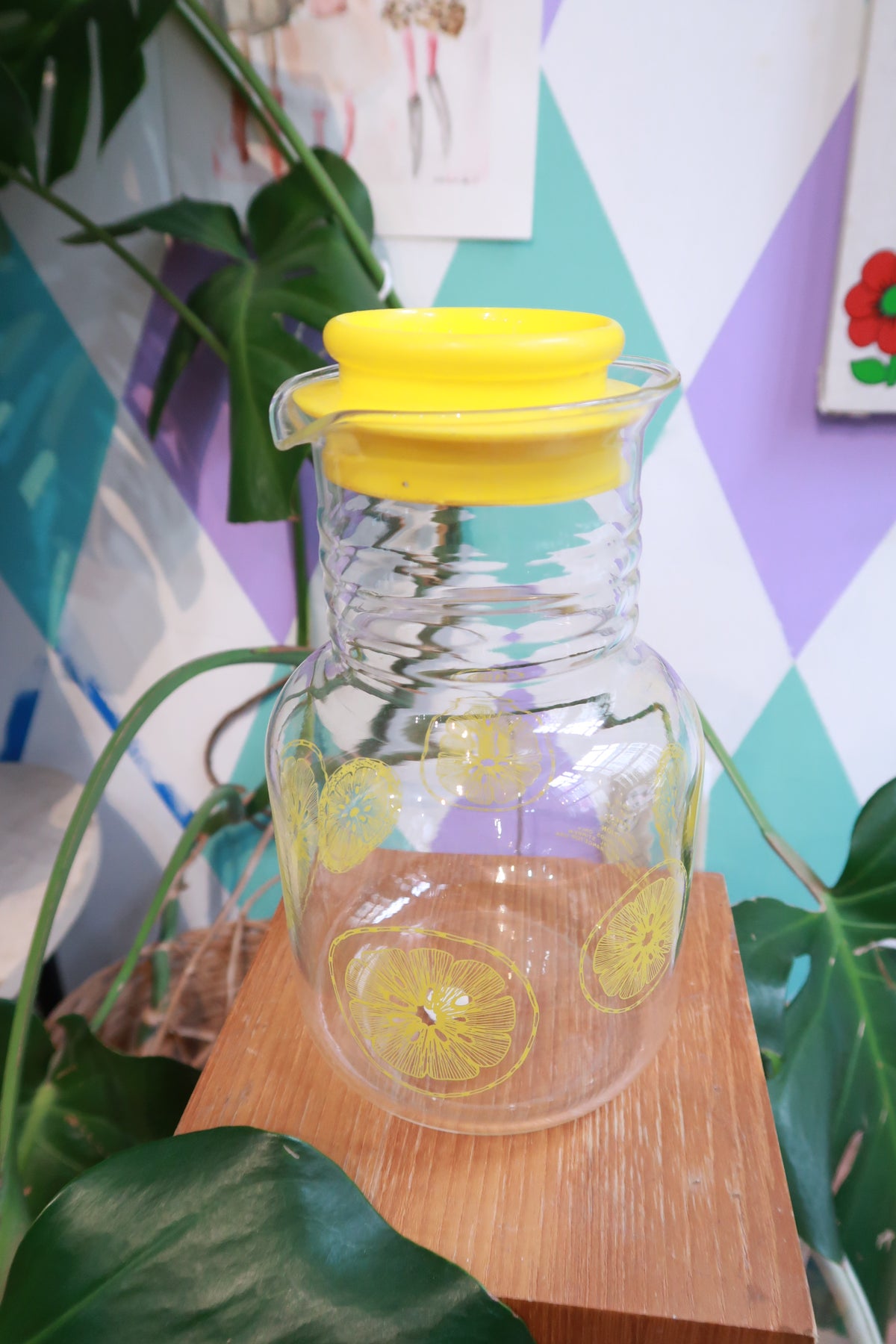 Vintage lemon print glass pitcher with yellow lid by Elektra Vintage, designed for serving citrus juice in a retro style.