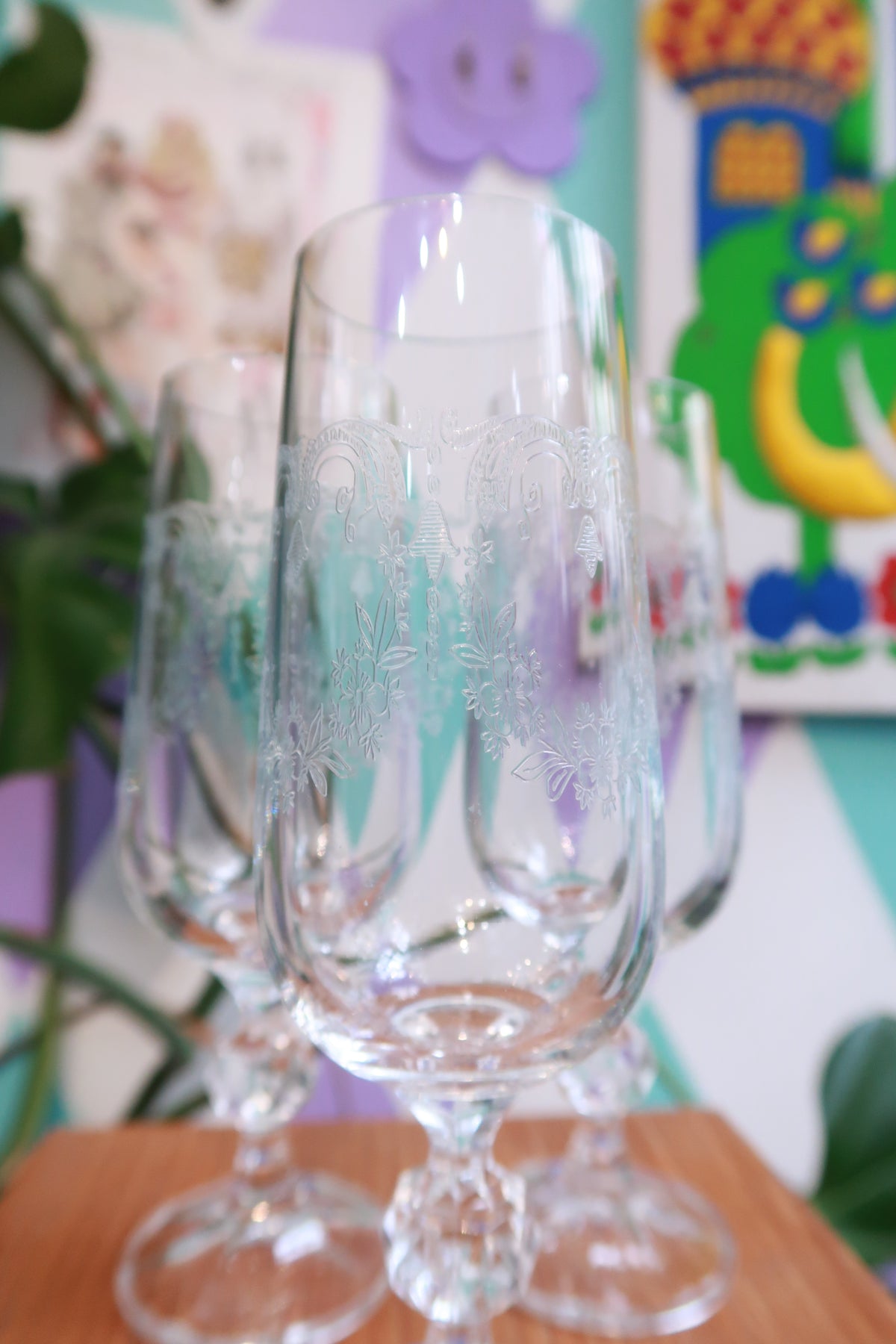 Pair of vintage etched crystal champagne flutes with faceted stems and floral designs by Elektra Vintage on clear crystal glass.