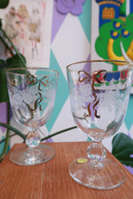 Load image into Gallery viewer, Set of two vintage etched floral wine glasses with gold bow trim, retro stemmed glass goblets by Elektra Vintage.
