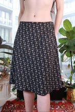 Load image into Gallery viewer, Black vintage 2000s floral midi skirt by Elektra Vintage, flowy A-line design with ditsy floral pattern, perfect for Y2K fashion.

