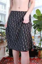 Load image into Gallery viewer, Black ditsy floral midi skirt by Elektra Vintage featuring a flowy A-line silhouette, vintage 2000s Y2K fashion style.
