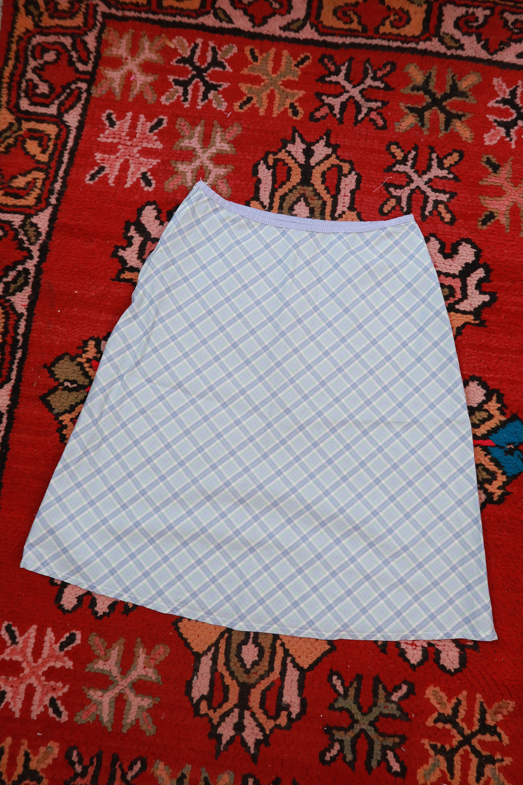 Vintage 2000s pastel blue plaid cotton midi skirt for women from Elektra Vintage, shown laid flat with pleats and waistband detail.