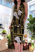 Load image into Gallery viewer, Vintage 2000s black and gold geometric floral halter mini dress with ring detail by Elektra Vintage, shown on a hanger.
