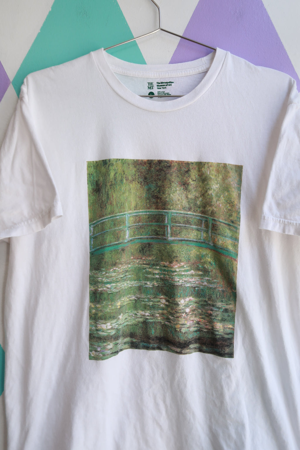 Men's graphic T-shirt featuring The Met Claude Monet Water Lilies Bridge artwork by Elektra Vintage, with vibrant water lily scene.